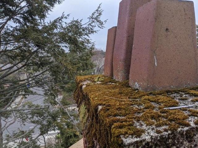 Chimney cap showing clear signs of water damage. Cracks and algae growth are indicators of moisture damaging your cap.