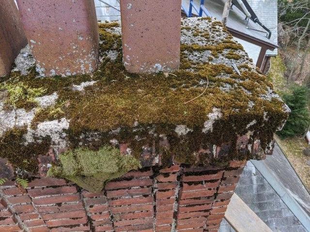 Chimney cap showing clear signs of water damage. Cracks and algae growth are indicators of moisture damaging your cap.