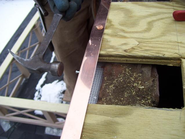 This close up shot shows one of our crew members carefully nailing in the copper trim, making sure it is tight to the chimney around every edge.
