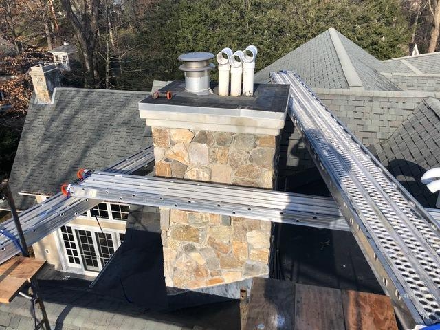 Repairing chimney cap on a shingle roof.