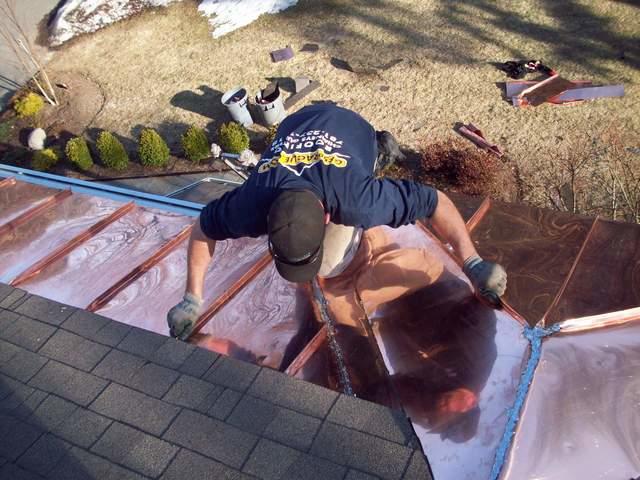 Our craftsmen installing copper panels into the edge of the roof.

