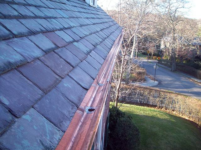Smooth copper gutter transition to a slate roof.