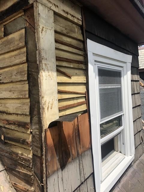 Rotting and deteriorating wood shingles on a dormer roof.

