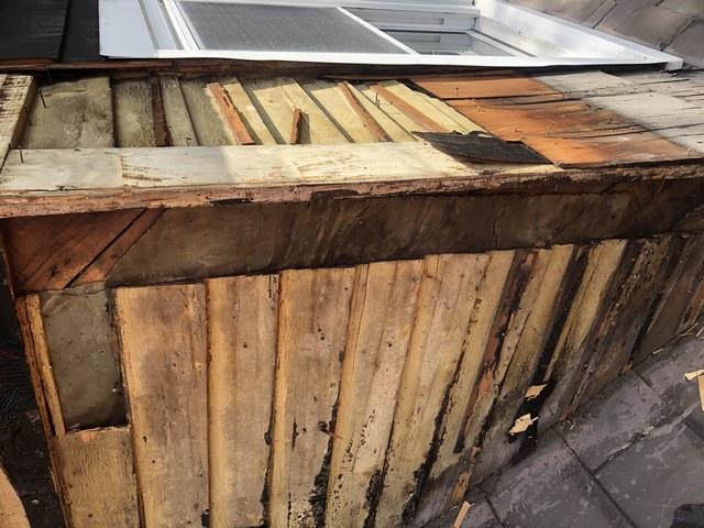 Rotting and deteriorating wood shingles on a dormer roof.

