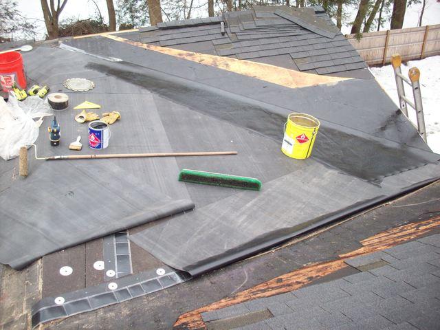 We see this project in progress, as the existing roof has already been stripped off and the underlayments for the new roof have been installed. The rubber for the roof has been laid out and just needs to be installed and some of the shingles replaced as well.
