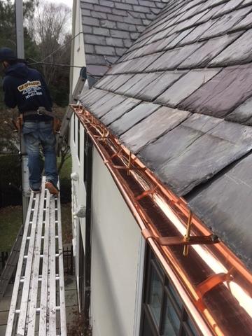 The copper gutters have been installed, and the slates run right up to the gutter line so water can easily run off the roof and into the gutters. These gutters will help rain and melted snow run down the gutters and downspouts rather than pouring right off the roof.