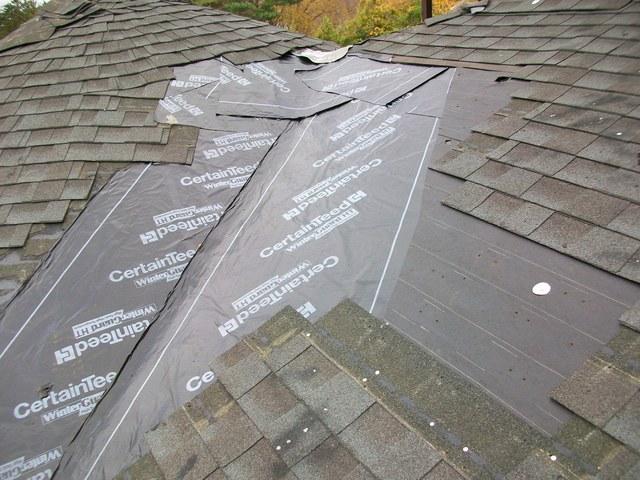We remove the existing damaged shingles first, revealing the poorly installed ice & water shield underneath.