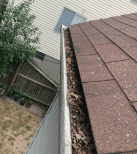 Clogged wooden gutters on an asphalt shingle roof.