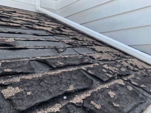 Broken asphalt shingle tiles needing a roof replacement.