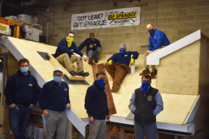 Craftsmen sitting on the mock training roof installed in our fabrication shop.