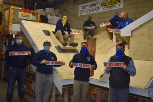 Our team holding "Got Ice Dams?" signs while sitting on the mock training roof.